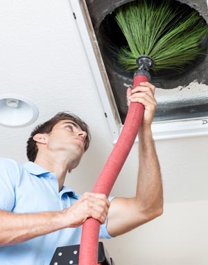 Technician cleaning an air duct in a home.